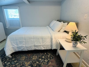 Ein Schlafzimmer mit einem Bett, einem Nachttisch, einer Lampe und einer Topfpflanze.