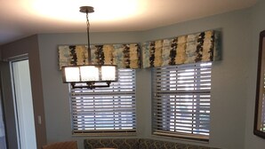 A dining area with a wooden table, four chairs, a bench, and a chandelier.