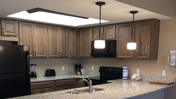 A modern kitchen with granite countertops, stainless steel appliances, and wooden cabinets.