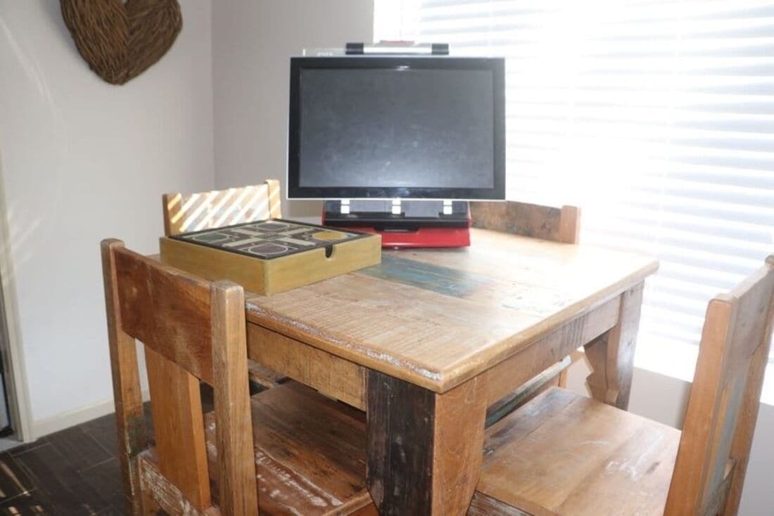 Una mesa de madera con un televisor encima, una caja con un diseño geométrico y una decoración de pared tejida.