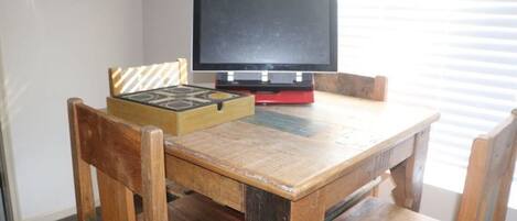 Una mesa de madera con un televisor encima, una caja con un diseño geométrico y una decoración de pared tejida.
