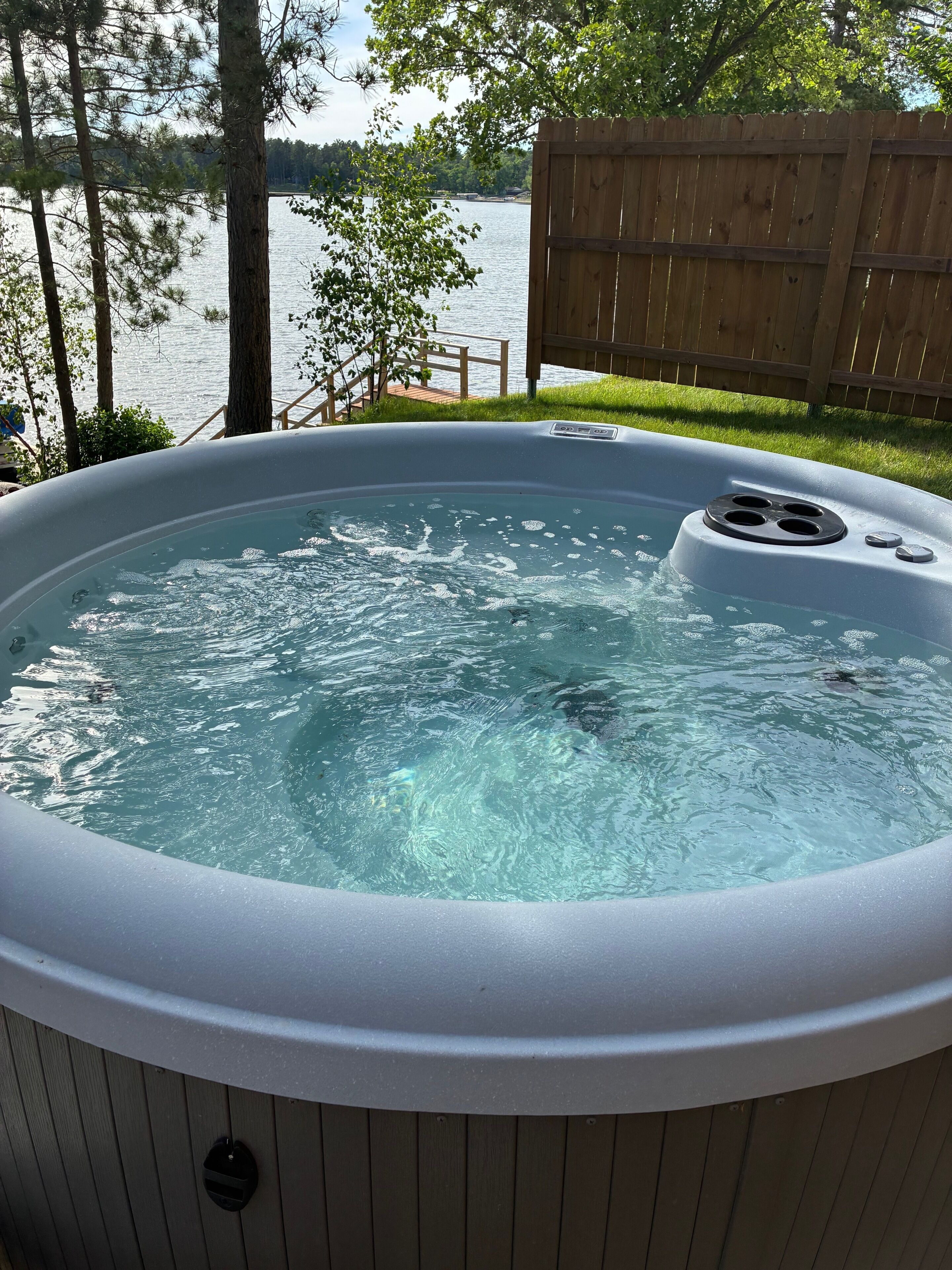 Un bain à remous avec une terrasse en bois et vue sur un lac.