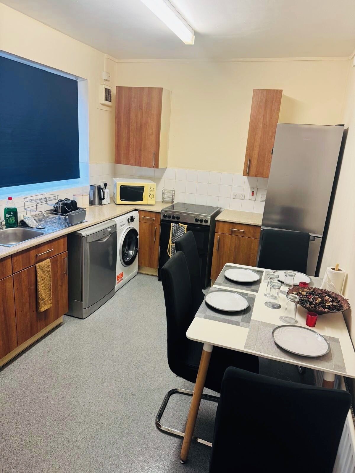 Une cuisine compacte équipée d’un lave-linge, d’un four à micro-ondes, d’une cuisinière et d’un réfrigérateur.