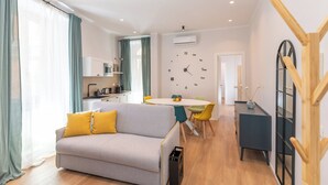 Een moderne woonkamer met een bank, een eettafel en een keuken op de achtergrond.