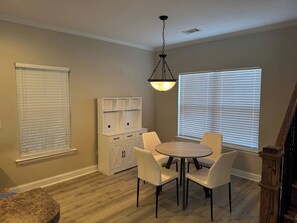 A dining area with a round table and four chairs, a white cabinet with drawers, and a hanging light fixture. - Stylish 2BR, Parking | Masters & Medical District (Augusta)