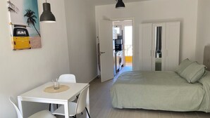 A compact room with a bed, a dining table with chairs, a kitchenette, and a door leading to an outdoor area. - Palmeraie Studio - Sea view and pool (Puerto de la Cruz)