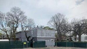 A parking lot with a building that has a gray exterior and a covered entrance.