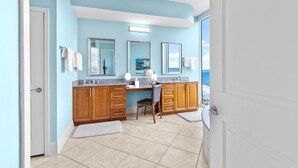Un baño con pared azul, armarios de madera, un lavamanos y una silla.