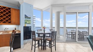 Una cocina moderna con espacio para vinos, un comedor con mesa redonda y sillas, y un balcón con vistas al mar.