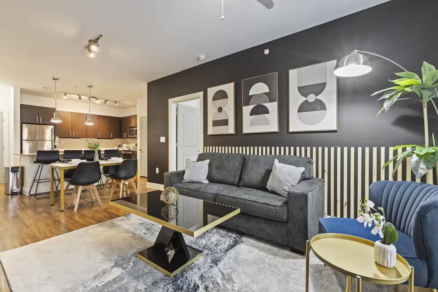 A modern living room with a grey sofa, a coffee table, and a dining area with a table and chairs.