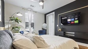 A modern bedroom with a bed, bedside tables, a TV mounted on the wall, and a ceiling fan. - Great for Children with bunk Beds (Frisco)