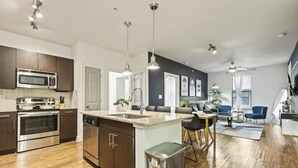 A modern kitchen with stainless steel appliances, a central island, and pendant lighting. - Great for Children with bunk Beds (Frisco)