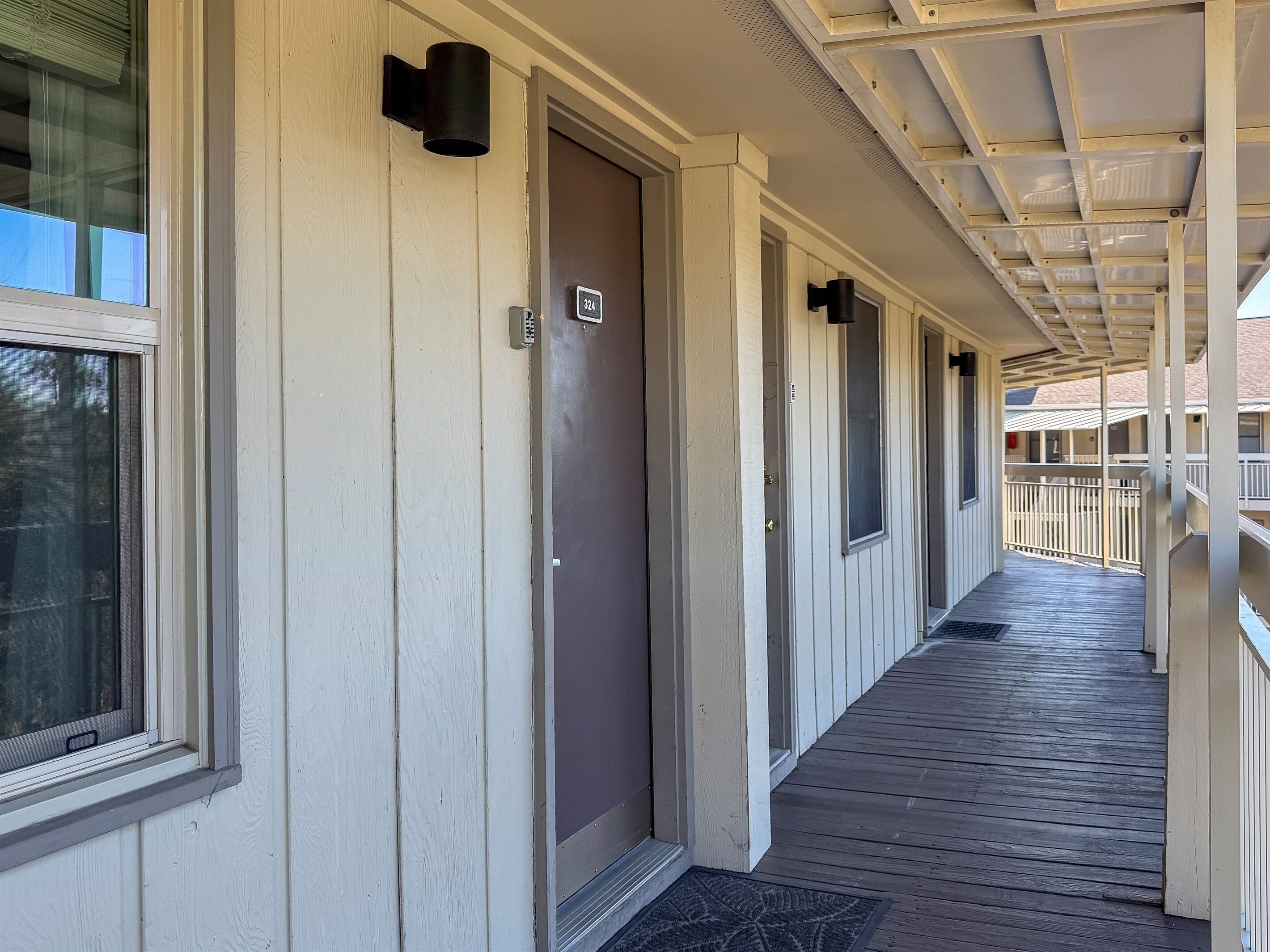 A corridor with doors, a number sign, and a wooden deck.