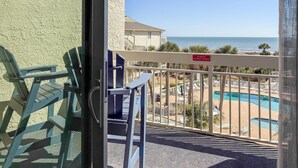 A balcony with a view of a pool and beach, a 'No Grilling' sign, and a building with a textured wall. - Breakers 324 Oceanfront Hilton Head Condo Direct Beach Access (Hilton Head Island)