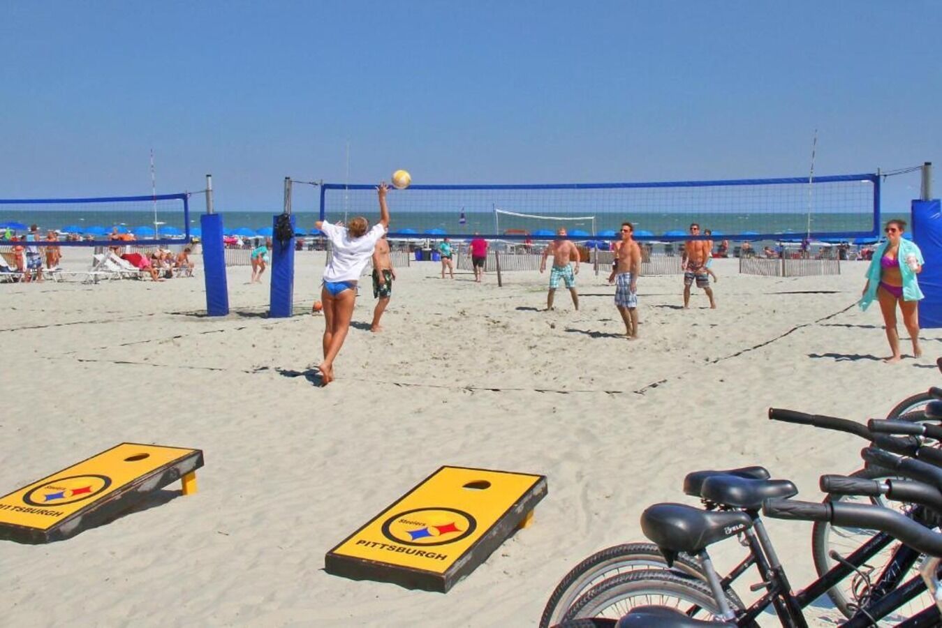 A beach volleyball game with players and spectators.