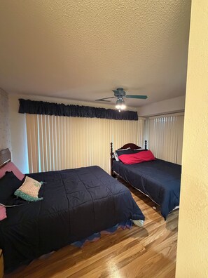 Ein Schlafzimmer mit zwei Einzelbetten, einem Deckenventilator und einem Fenster mit Jalousien.