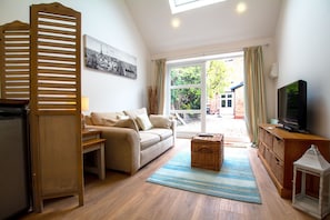 Una sala de estar con sofá, televisor, un mueble de madera y ventana con cortinas.