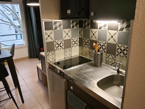 A compact kitchen with a modern design, featuring a black and white patterned backsplash, a stainless steel sink, and a built-in dishwasher. - Cocorico d'Avignon (Avignon)