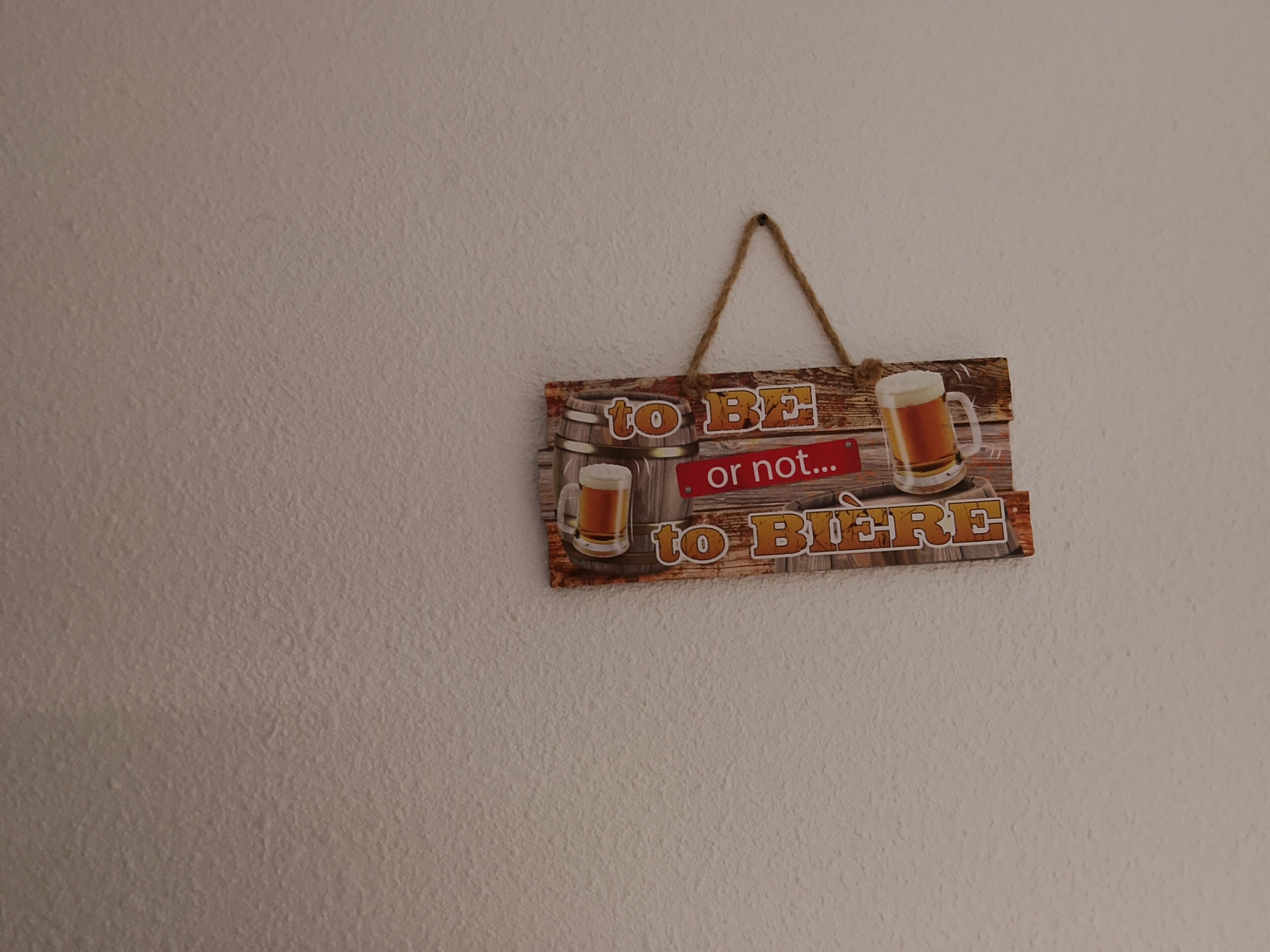 A wooden sign with a handle, featuring a beer mug and the text "to be or not to be to beer".
