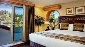 Una camera d'albergo con un letto grande, una finestra con tende, uno specchio rotondo e vista sull'esterno.