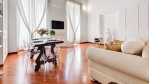 Ein geräumiges Wohnzimmer mit Holzboden, einer Essecke mit Tisch und Stühlen sowie einem Sofa.