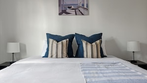 A hotel room with a large bed, two nightstands, a painting of a balcony, and a view of the sea. - 1 King 2 Queens Garage Yard Washer Dryer (Old Hickory)