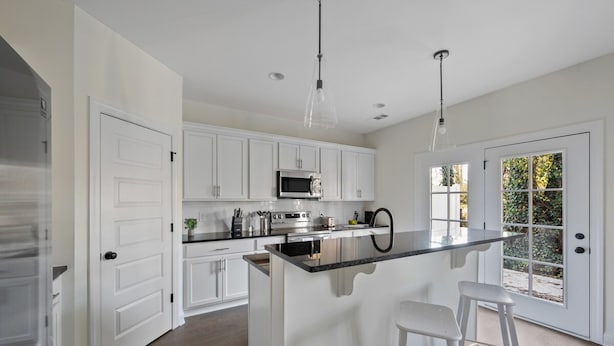A modern kitchen with white cabinets, a central island with bar stools, a microwave, and a sink. - 1 King 2 Queens Garage Yard Washer Dryer (Old Hickory)