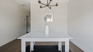 A dining area with a white table, a modern chandelier, and a vase with greenery. - 1 King 2 Queens Garage Yard Washer Dryer (Old Hickory)
