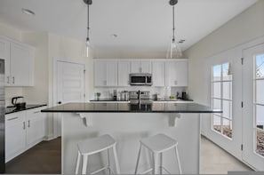 A modern kitchen with white cabinets, a black countertop, stainless steel appliances, and pendant lighting. - 1 King 2 Queens Garage Yard Washer Dryer (Old Hickory)
