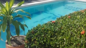A swimming pool with lounge chairs and a thatched roof structure. - Hotel Villas Punta Peñasco (Acapulco)