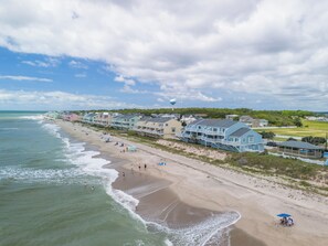 A coastal hotel with beachfront rooms, a sandy beach, and a water tower in the background. - Cozy 2-bedroom townhome in charming Kure Beach - 4 pools and rec center (Kure Beach)