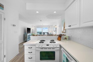A modern kitchen with white cabinets, a stove, and an oven. - Cozy 2-bedroom townhome in charming Kure Beach - 4 pools and rec center (Kure Beach)