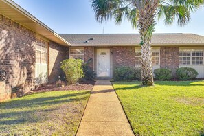 A two-story house with a brick exterior, a front door, and a small front yard with a palm tree and shrubs. - Best of Destin & Fort Walton Coastal Retreat (Fort Walton Beach)