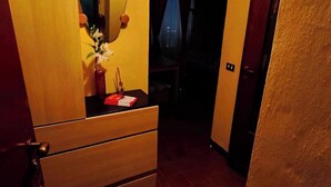 A room with a wooden dresser, a mirror, and a small table with a vase of flowers. - Wooden loft with balcony (metro and services under the house) sleeps 4 (Milano)