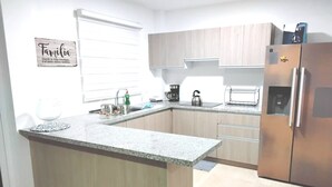 Una cocina con encimera de granito, armarios de madera, refrigerador de acero inoxidable y cafetera.