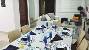 Comedor con una mesa dispuesta para seis personas, con vajilla y cristalería azul y blanca.