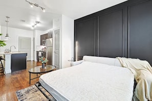 Una camera da letto moderna con un letto grande, un tavolino rotondo e vista sulla cucina.