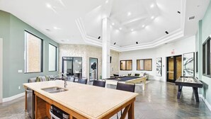 A spacious living area with a pool table, a kitchen with a wooden island, and a seating area with a sofa and chairs. - Lux 1B w Pool Near Toyota HQ (Frisco)