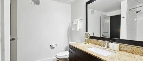 Une salle de bain moderne avec des toilettes, un lavabo et un miroir.