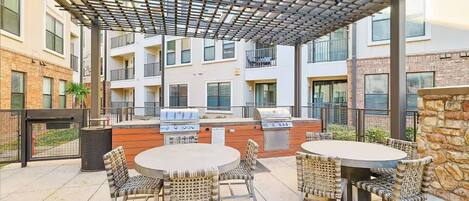 An outdoor patio with a grill, wicker chairs, and a pergola.
