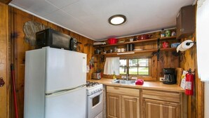 Una cocina compacta con refrigerador, estufa y armarios de madera.