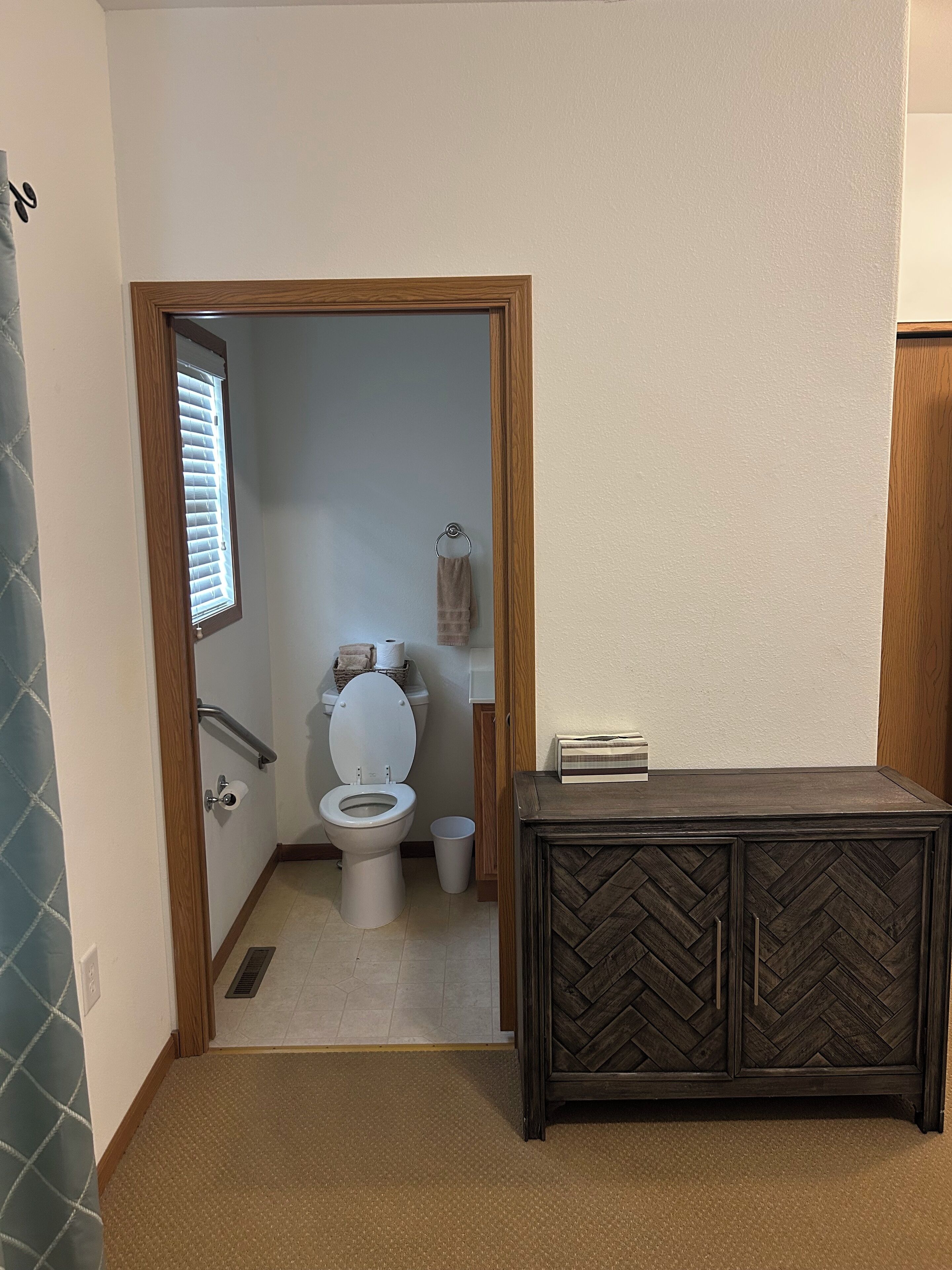 A bathroom with a toilet, a towel rack, and a cabinet.