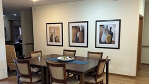 Un coin repas avec une table et des chaises en bois, des œuvres d’art encadrées accrochées au mur et un plancher en bois.