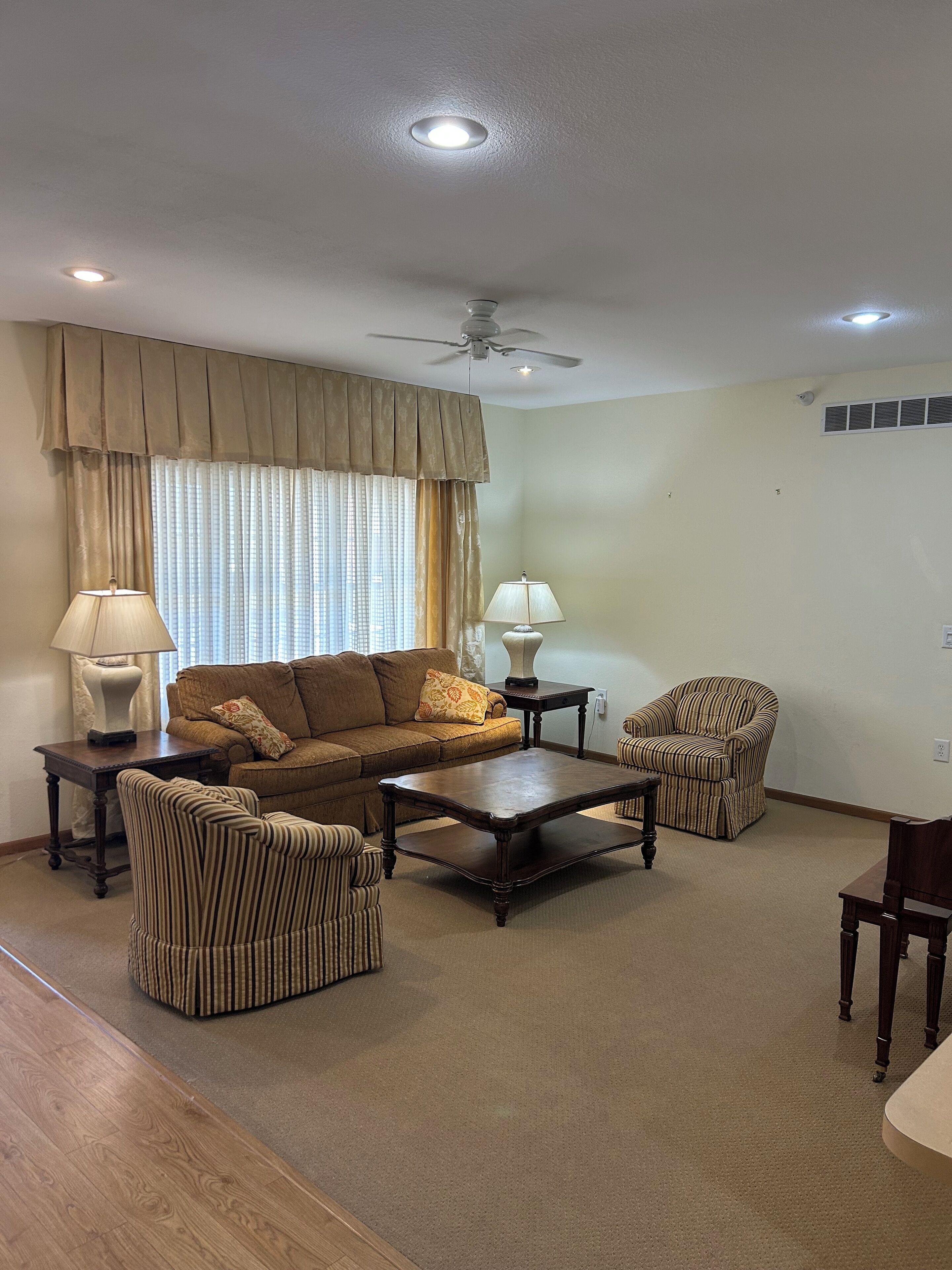 A living room with a sofa, armchairs, a coffee table, and two lamps.