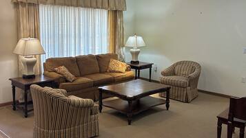 A living room with a sofa, armchairs, a coffee table, and two lamps.