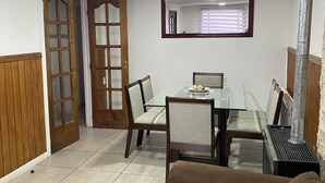 A dining area with a table, chairs, and a mirror above it. There is a wooden door and a window with blinds. - Spacious and comfortable house, excellent heating. (Punta Arenas)