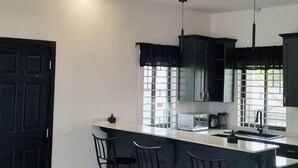 Cocina moderna con isla central, taburetes de bar e iluminación colgante.
