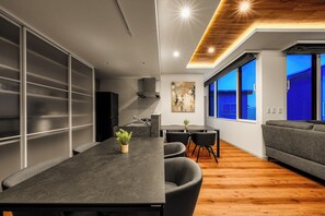 A modern kitchen with a dining area, a sofa, and a large window with a view. - TDR Toti Design Room (Furano)