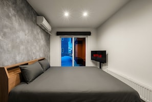 A modern bedroom with a large bed, a flat-screen TV, and an air conditioning unit. - TDR Toti Design Room (Furano)