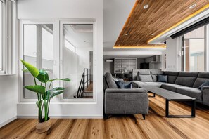 A modern living room with a grey sectional sofa, a coffee table, and a large green plant. - TDR Toti Design Room (Furano)